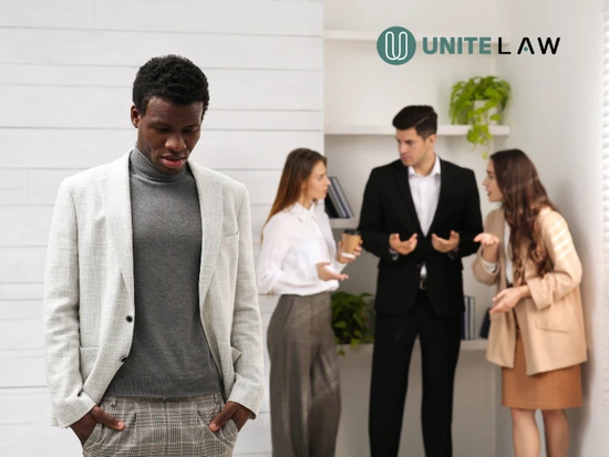 Employeea being excluded a tense office environment while coworkers argue in the background, representing a hostile work environment in Connecticut and workplace harassment concerns